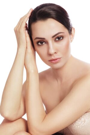Young beautiful healthy thoughtful woman touching her face over white backgroundの写真素材