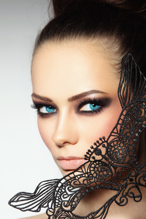 Close-up portrait of young beautiful woman with smoky eyes and lacy black maskの写真素材