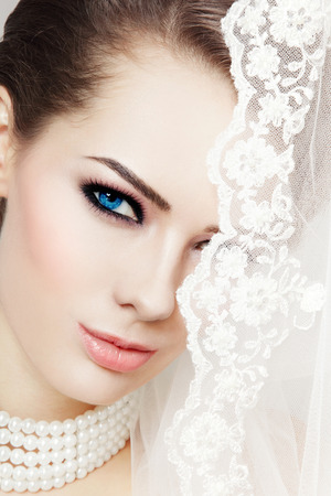 Close-up portrait of young beautiful bride with stylish make-up and bridal veilの写真素材
