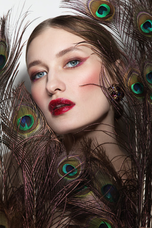 Glamorous portrait of young beautiful woman in peacock feathersの写真素材
