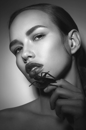 Vintage style black and white portrait of young beautiful woman with bug in her handの写真素材