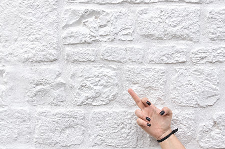 a woman gestures to fuck off on a white wall textureの写真素材