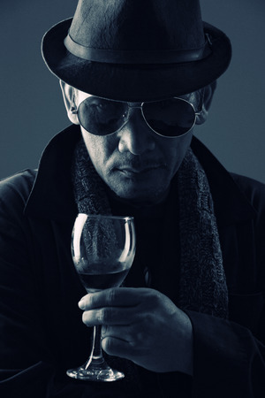 Portrait of criminal mastermind in suit holding glass of wineの写真素材