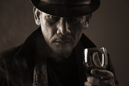 Portrait of mature aged gangster holding a glass of wineの写真素材