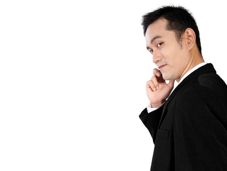 Side view of young Asian businessman making a phone call turning his head toward camera isolated on white backgroundの写真素材