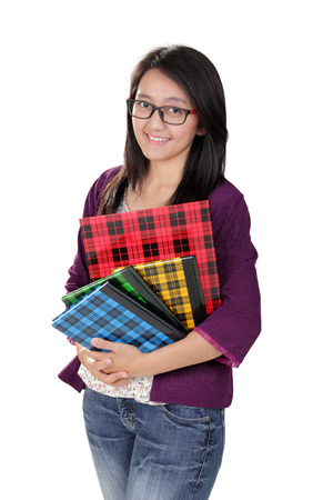 Friendly Asian student girl smiling and holding some books, isolated on white backgroundの写真素材
