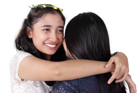 Young Asian woman with gorgeous smile giving a hug to her girl friend, isolated on white backgroundの写真素材