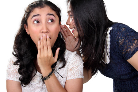 Surprised face expression of Asian girl when she heard a gossip her friend told, isolated on white backgroundの写真素材