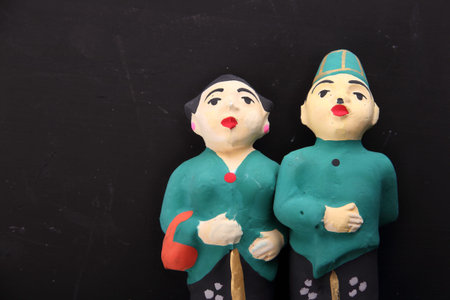 Handmade sculpture of Indonesian wedding couple in traditional costume, over blackboard backgroundの写真素材