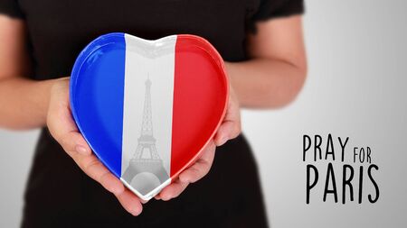 Pray for Paris, illustrated with image of hands holding heart shaped box in France flag colors and Eiffel Tower graphicの写真素材