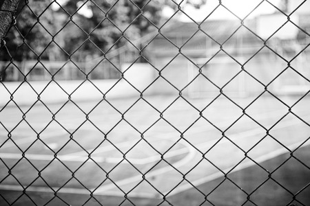 View of a basketball court through the fence, in black and whiteの写真素材