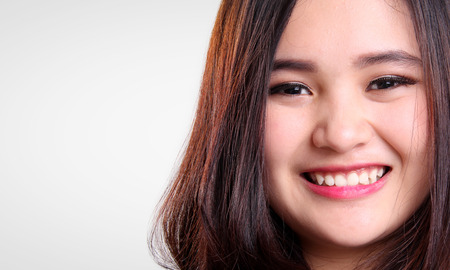 Close up face of cute Asian teenage girl  smiling to camera, isolated on white background with copy spaceの写真素材