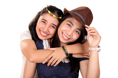 Two attractive Asian hipster girls hugging and smiling at camera, isolated on white backgroundの写真素材