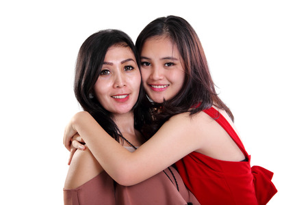 Lovely Asian mother and daughter embracing and smiling to camera, isolated on white backgroundの写真素材