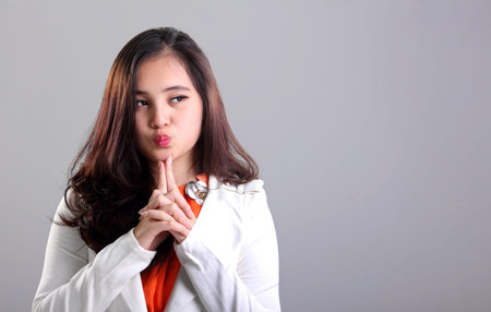 Attractive Asian girl in white suit making cute face while looking at empty space on her sideの写真素材