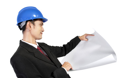Young Asian architect looking at a paper scroll, isolated on white backgroundの写真素材