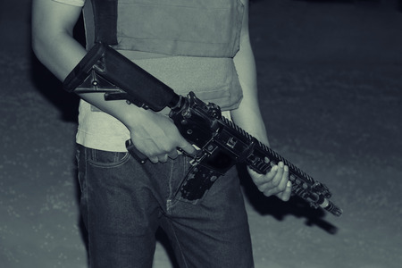 Armed man hands carrying a rifle in a battlefield, night vision portrait, war conceptの写真素材