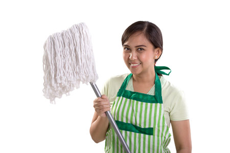 Young Asian woman in apron smiling at camera while holding a mopping stick, isolated over white...