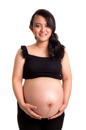 Portrait of eight months old pregnancy lady smiling at camera, isolated over white backgroundの写真素材