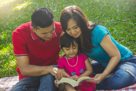 Close up portrait of a family reading book together in a parkの写真素材