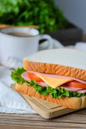 sandwich with ham, cheese and vegetables,and coffee on wood tableの写真素材