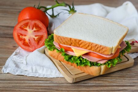 sandwich with ham, cheese and vegetables on wood tableの写真素材