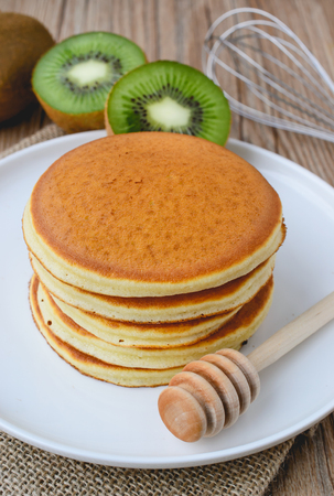 stack of pancake on white plate and sackcloth with kiwi slices on wood backgroundの写真素材