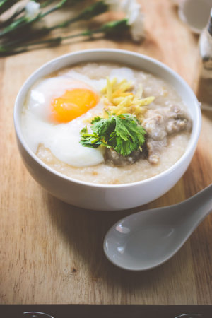 rice porridge with ground pock vintage tone with white flowers on wood background, Thai Food, Thai...