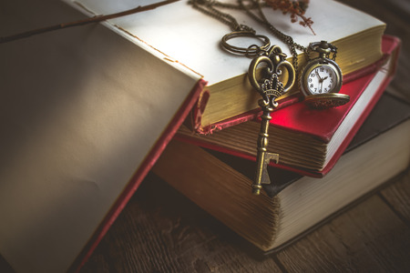 Pocket watch and Old vintage key on  stack of old book with copy space in morning light for time, unlock or eductaion conceptの写真素材