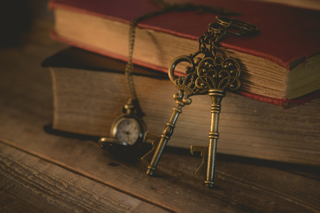 close-up old key and pocket watch with stack of book on night light in vintage tone, waiting, unlock conceptの写真素材