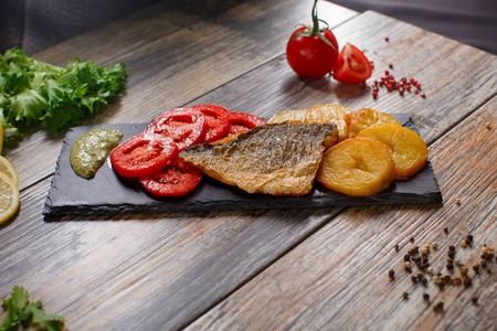 dorado fish with potatoes and tomatoesの写真素材