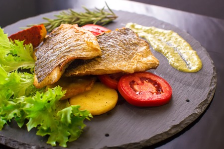 dorado fish with potatoes and tomatoesの写真素材