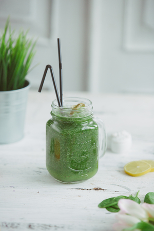 Blended green smoothie with ingredients on wooden tableの写真素材