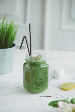 Blended green smoothie with ingredients on wooden tableの写真素材