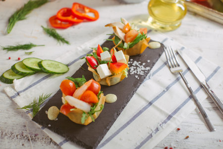 Fresh vegetable salad with shrimps and feta cheese on a white plate on a wooden table