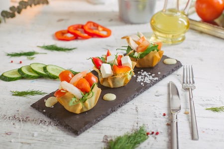 Fresh vegetable salad with shrimps and feta cheese on a white plate on a wooden tableの写真素材