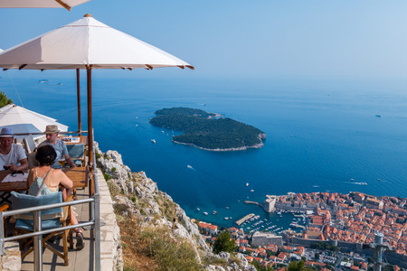People in a restaurant above Dubrovnik.  Dubrovnik, Croatia - July 18, 2015: Two men and one woman in a restaurant on top of the mountain above Dubrovnik.  Summer view of Dubrovnik.のeditorial素材