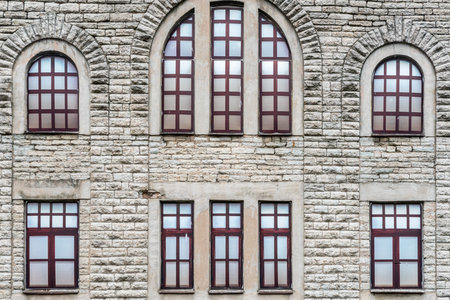 Old worn brick front exterior of industrial building, Tallinn Estonia. Plastic window decoration in window arches.
