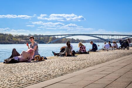 People relaxing on a quay. Stockholm, Sweden - May 01, 2017: Many young people sitting and laying on a quay in the center of Stockholm. Relaxing and sunbathing, water and bridge in the background.のeditorial素材