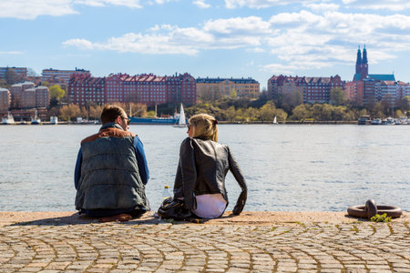 Man and woman on a quay. Stockholm, Sweden - May 01, 2017: Caucasian man and woman sitting close...