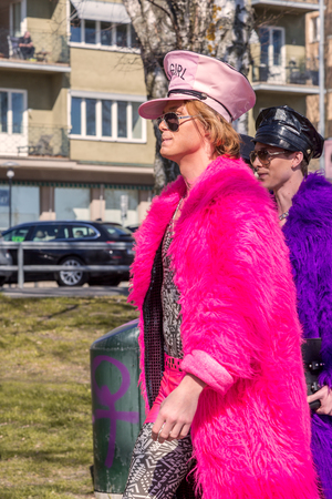 Two men in colorful furs. Stockholm, Sweden - May 01, 2017: Two caucasian men showing off in colorful fake furs and hats walking together in a park in central Stockholm. Background with a blurred man.のeditorial素材