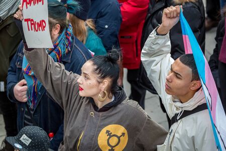 Stockholm, Sweden - January 21, 2017: Close up image of two young multi ethnic activists at a public square holding sign and flag about to join a demonstration.のeditorial素材