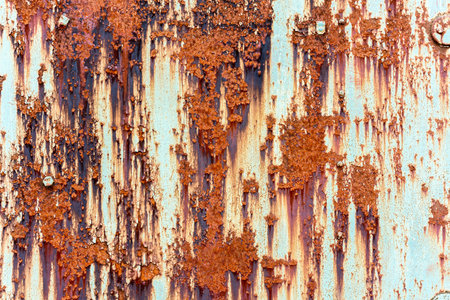 Old red rusty metallic steel plate with flaking paint. Weathered grungy texture outdoors.