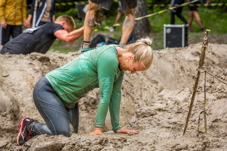 Stockholm, Sweden - June 03, 2017: Close up side view, one exhausted caucasian woman in a mud...