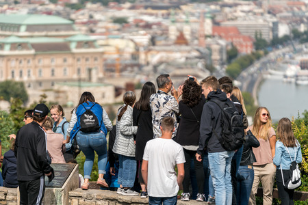 Budapest, Hungary - September 26, 2017: Selective focus back view of a mixed group of young and old tourists standing at a viewpoint up high to take panoramic pictures of the city Budapest Hungary below.のeditorial素材