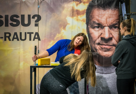 STOCKHOLM, SWEDEN - JANUARY 13, 2018: Two female arm wrestlers and one spectator training in front of a large ad during the event Arm Battle of Sweden outside of Sockholm January 13, 2018.のeditorial素材