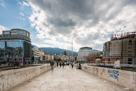 SKOPJE, MACEDONIA - SEPTEMBER 22, 2016: Perspective view of people walking on a stone bridge in the city center of Skopje, Macedonia September 22, 2016. Modern buildings and construction on booth sides of the bridge.のeditorial素材