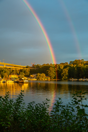 Evening view of a beautiful double rainbow over water and city.の写真素材