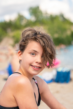 Close up summer portrait of a cute young girl with messy hair on a beach.の写真素材