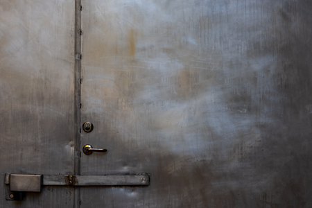 Closeup of closed scratched grungy shiny steel door with locks and handle.の写真素材